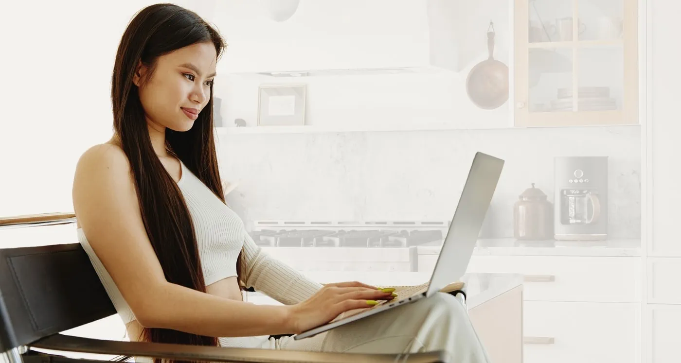 Woman typing on computer about how to know if you need a 12 Month Emergency Fund